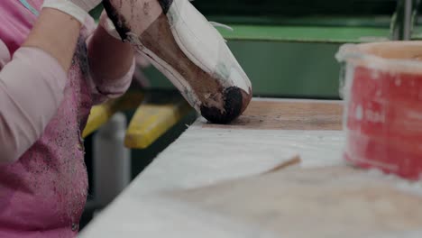 worker applying glue to a shoe before the sole gluing process in a factory