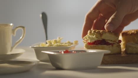 foto de cerca de una persona con el tradicional té de la tarde británico con crema de bollos y mermelada