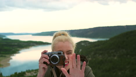 mujer riendo mientras toma fotos de un paisaje pintoresco con una cámara de época