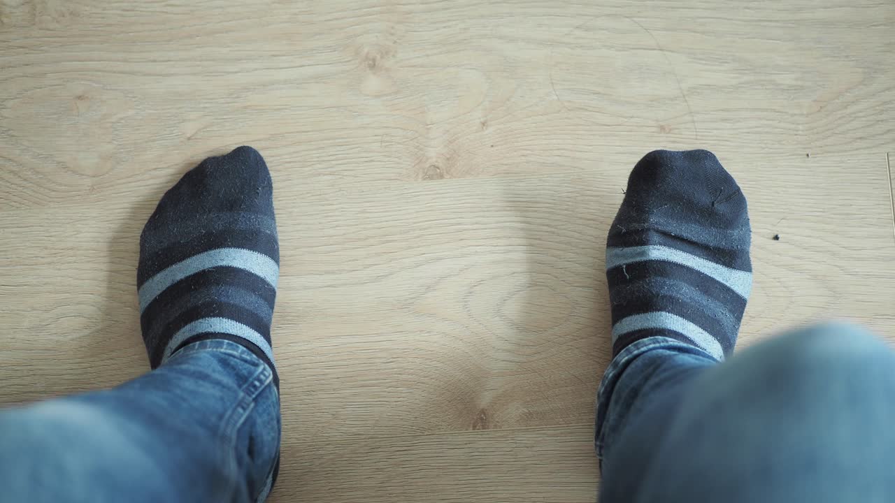 나무 바닥에 줄무 양말과 청바지를 입은 사람