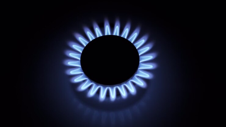Burning gas stove hob, blue flames macro close-up in the dark on a black background. Gas burner with slowly fading flame. 4k raw video with smooth camera movement.
