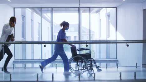 male doctor and female health worker with wheelchair running in the corridor at hospital