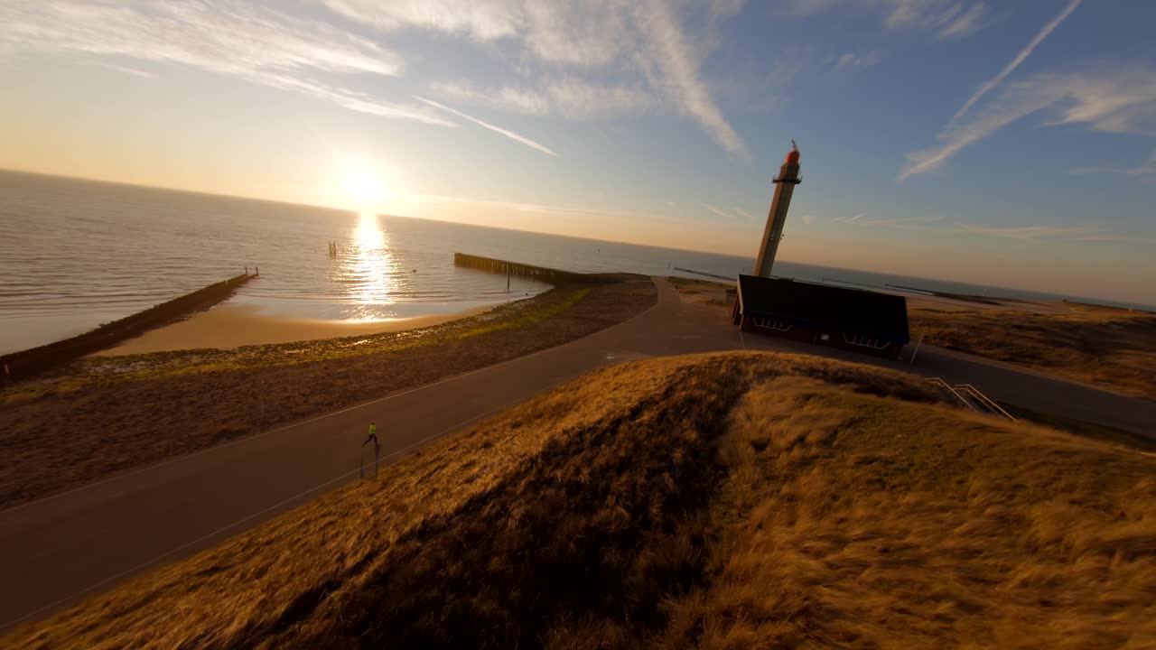 Fast drone shot flying above the dunes towards the lighthouse and pier