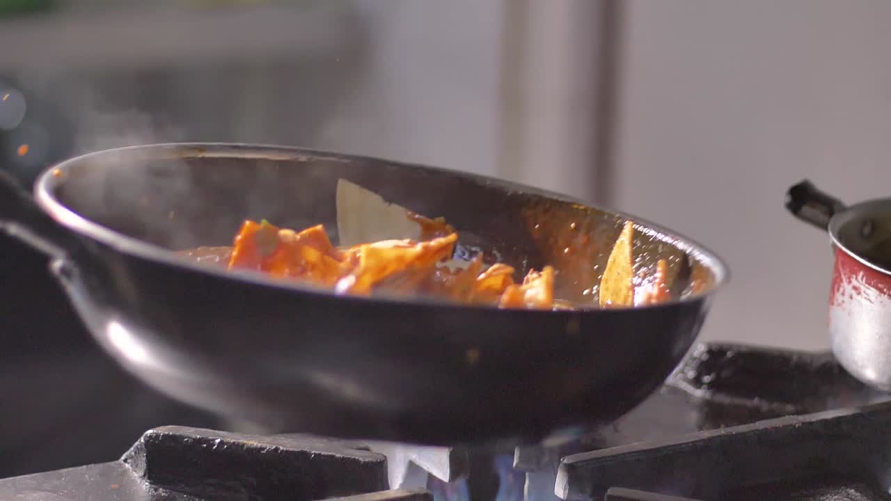 Tortilla chips con salsa piccante in padella su fuoco ardente al rallentatore