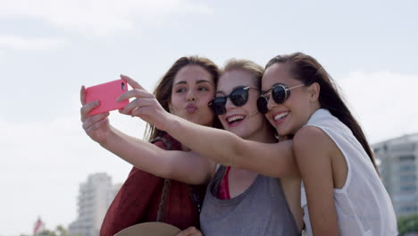 Group-of-teenage-girls-taking-selfie-using-smartphone-on-vacation-outdoors-beach-promenade