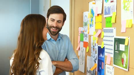 Business-colleagues-interacting-with-each-other-near-bulletin-board