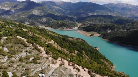 Antena-Pasando-Por-Turista-En-El-Mirador-Observando-La-Belleza-Del-Lago-Bovilla-En-Un-Día-Soleado