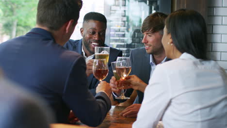 group of business colleagues meeting for drinks and socializing in bar after work