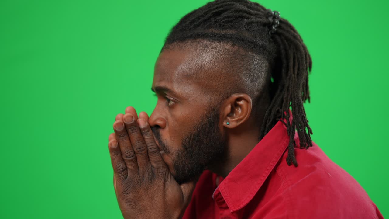 Anxious worried football fan supporting team reacting emotionally on green screen. Side view close-up of African American man watching soccer match at chromakey background.