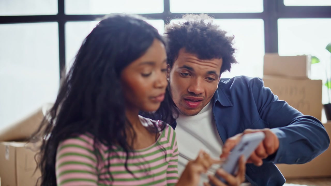 Homeowners pair discussing apartment using phone at new purchased home closeup