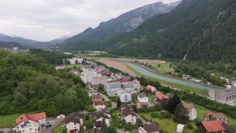 aerial wide shot of swiss village with river and green alp mountains in switzerland. cloudy summer day in domat ems