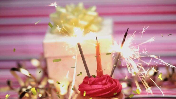 Animation de confettis dorés sur une main tenant une allumette allumant une bougie et des cierges magiques sur un cupcake d'anniversaire