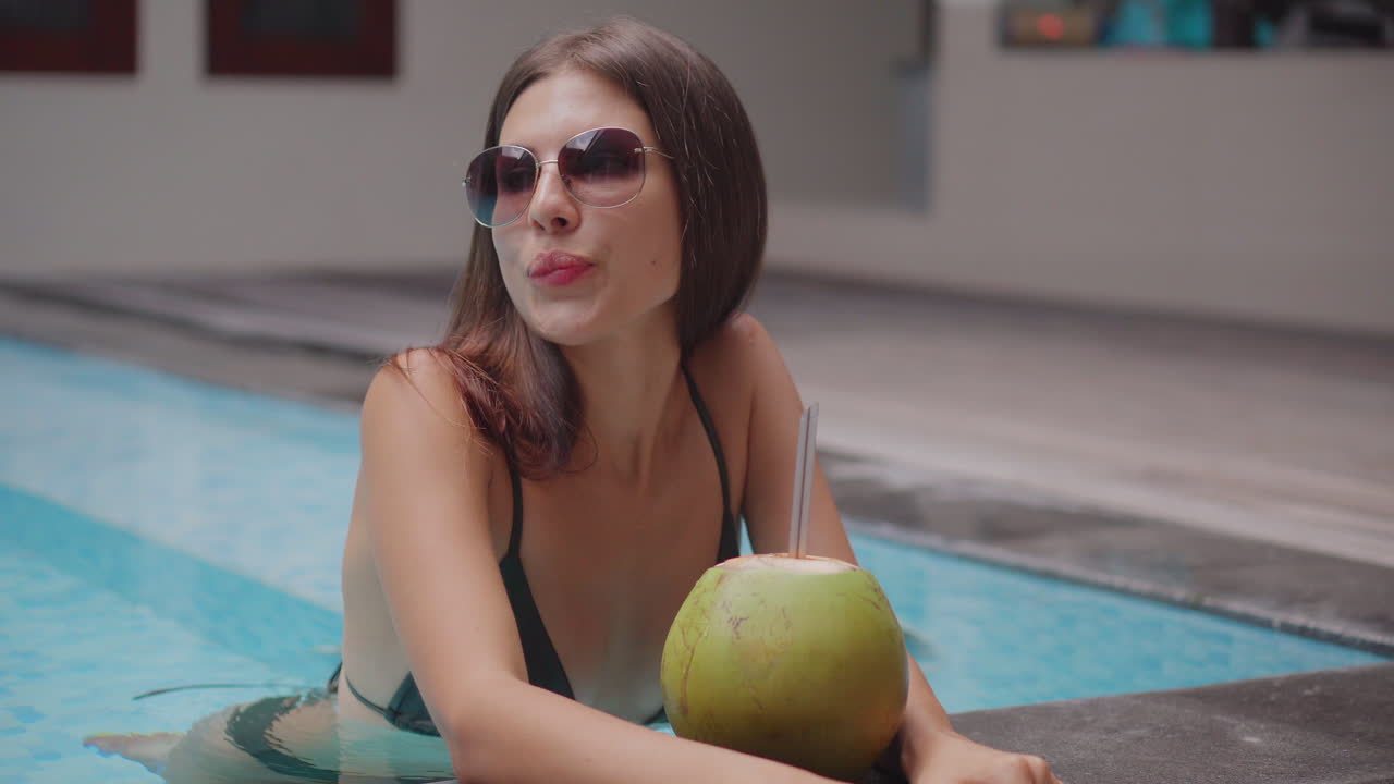 mujer disfrutando de un coco en una piscina