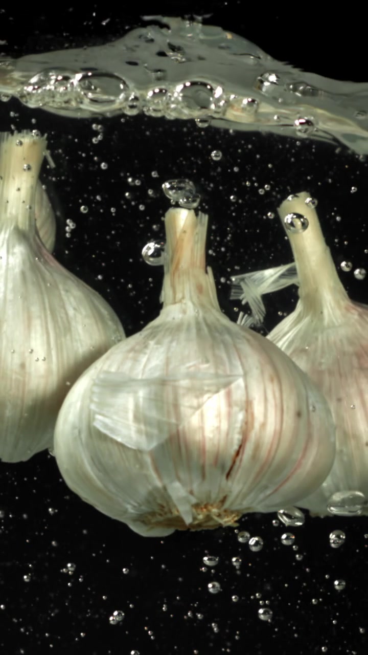 Teste d'aglio fresche immerse in acqua limpida con bolle