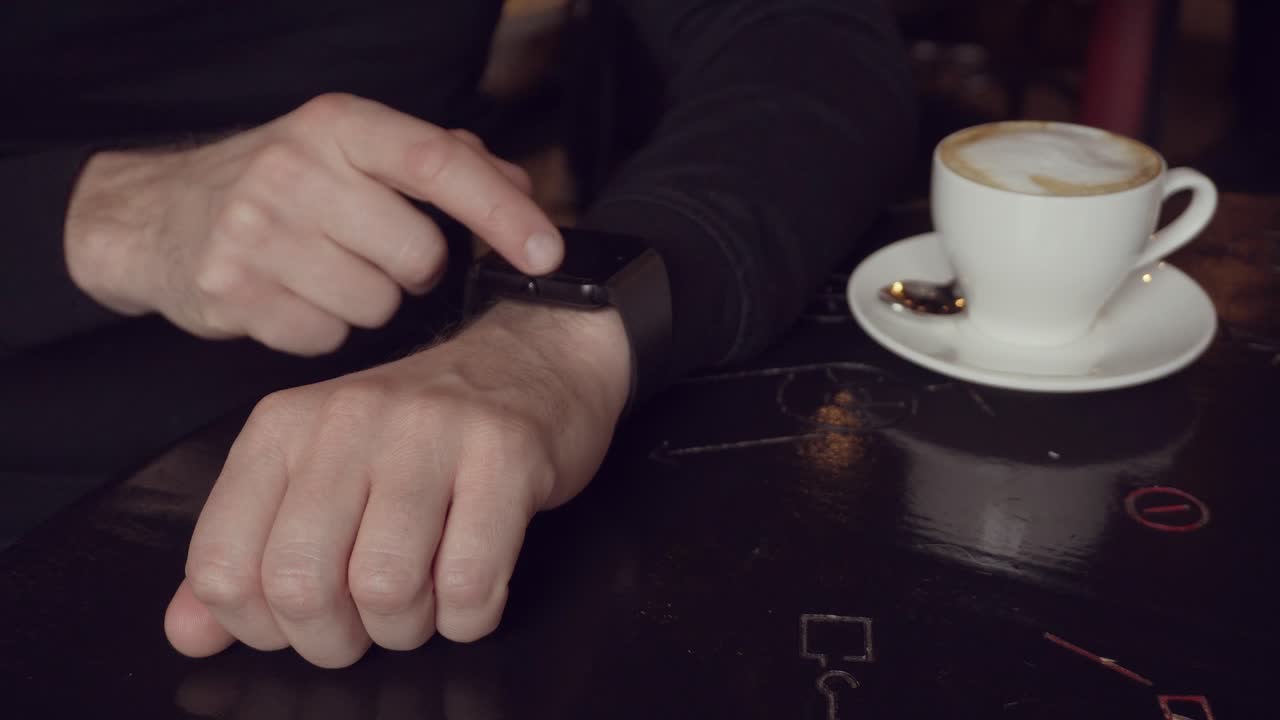 Man using smartwatch in a cafe