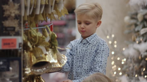 two kids picking up christmas tree decoration toys for christmas in a store