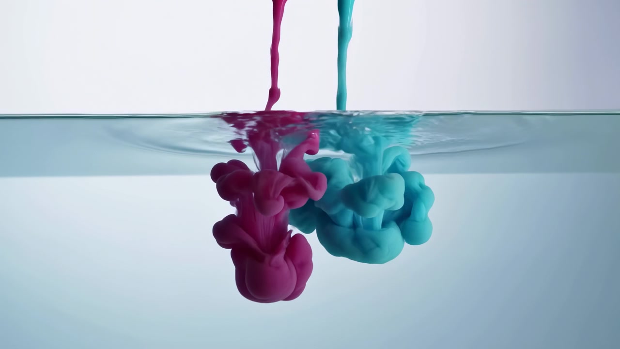 Magenta and cyan liquid streams descending into calm pale blue water, creating layered plumes, ripples, soft reflections, and fluid color movement beneath glossy surface in clean studio setting
