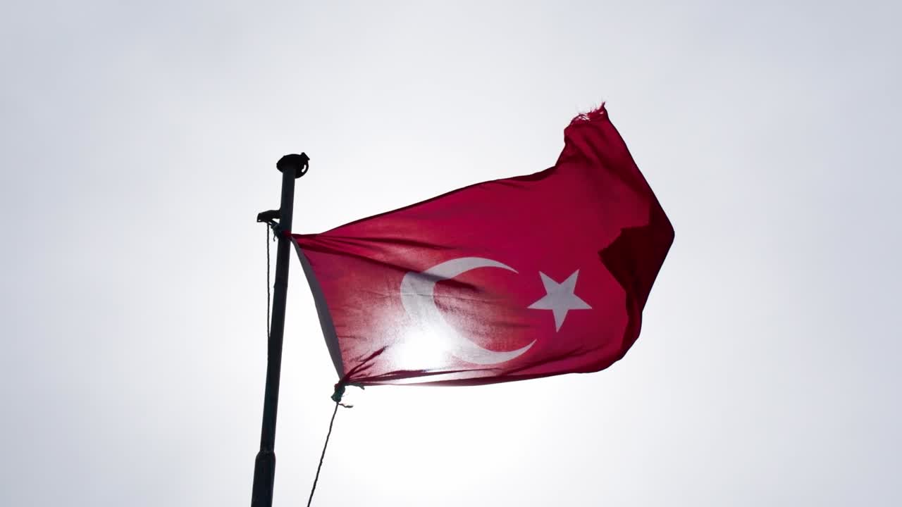 Ulusal Türkiye sembolü - Kapadokya vadileri üzerinde, dramatik bulut manzaralı bir tepede direğe asılı Türk bayrağı.