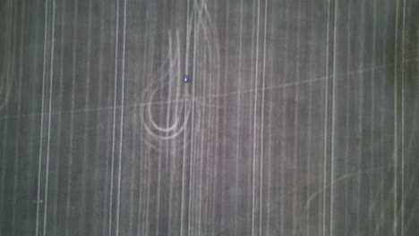 high altitude drone shot following a motorbike in an empty field