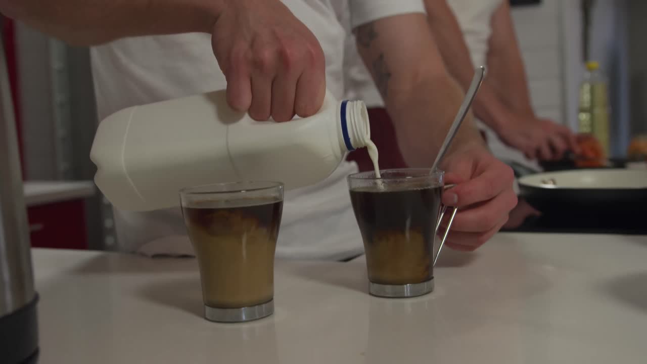 사회적 거리를 유지하는 백인 남성 커플이 집에서 함께 요리하고 있습니다.