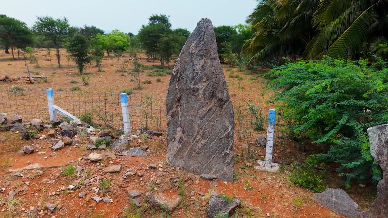 Ripresa con drone del sito di scavo megalitico di Kodumanal, Tamil Nadu, che mostra antichi menhir e cisti sepolcrali su terreno rosso arido, una delle più antiche scoperte archeologiche dell'India meridionale.
