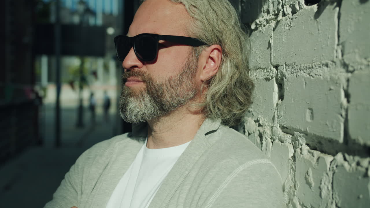 Man with sunglasses leaning against a brick wall