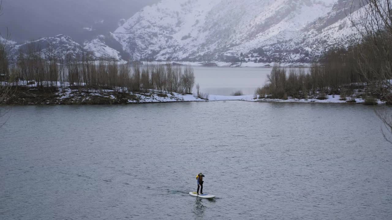 hombre en paddle board entre el agua y las montañas en la costa