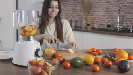 young pretty woman preparing fruit juice with blender