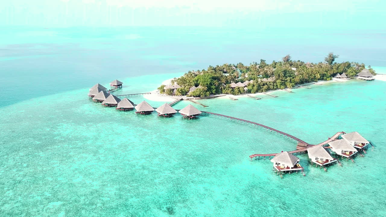 Ảnh chụp từ drone về hòn đảo nhỏ ở Maldives, khu nghỉ dưỡng nhiệt đới sang trọng với các bungalow trên mặt nước màu ngọc lam