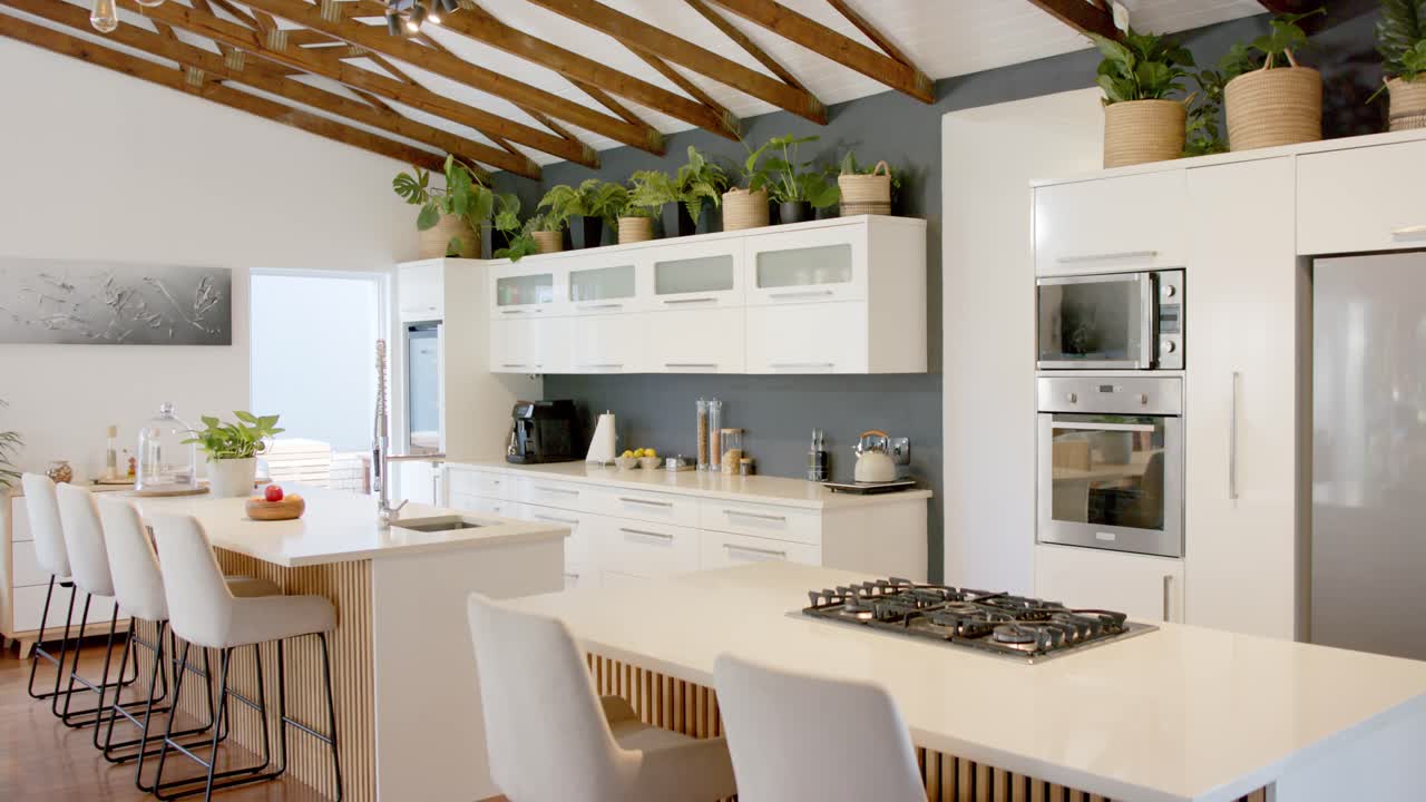 Câmera iniciando panorâmica para a esquerda, percorrendo uma ilha de cozinha branca com cooktop a gás, mostrando o layout completo.