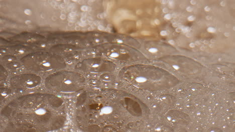 foaming liquid pouring container closeup. carbonated jet streaming making mousse