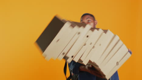 un repartidor torpe dejando caer una enorme pila de cajas de pizza en el estudio