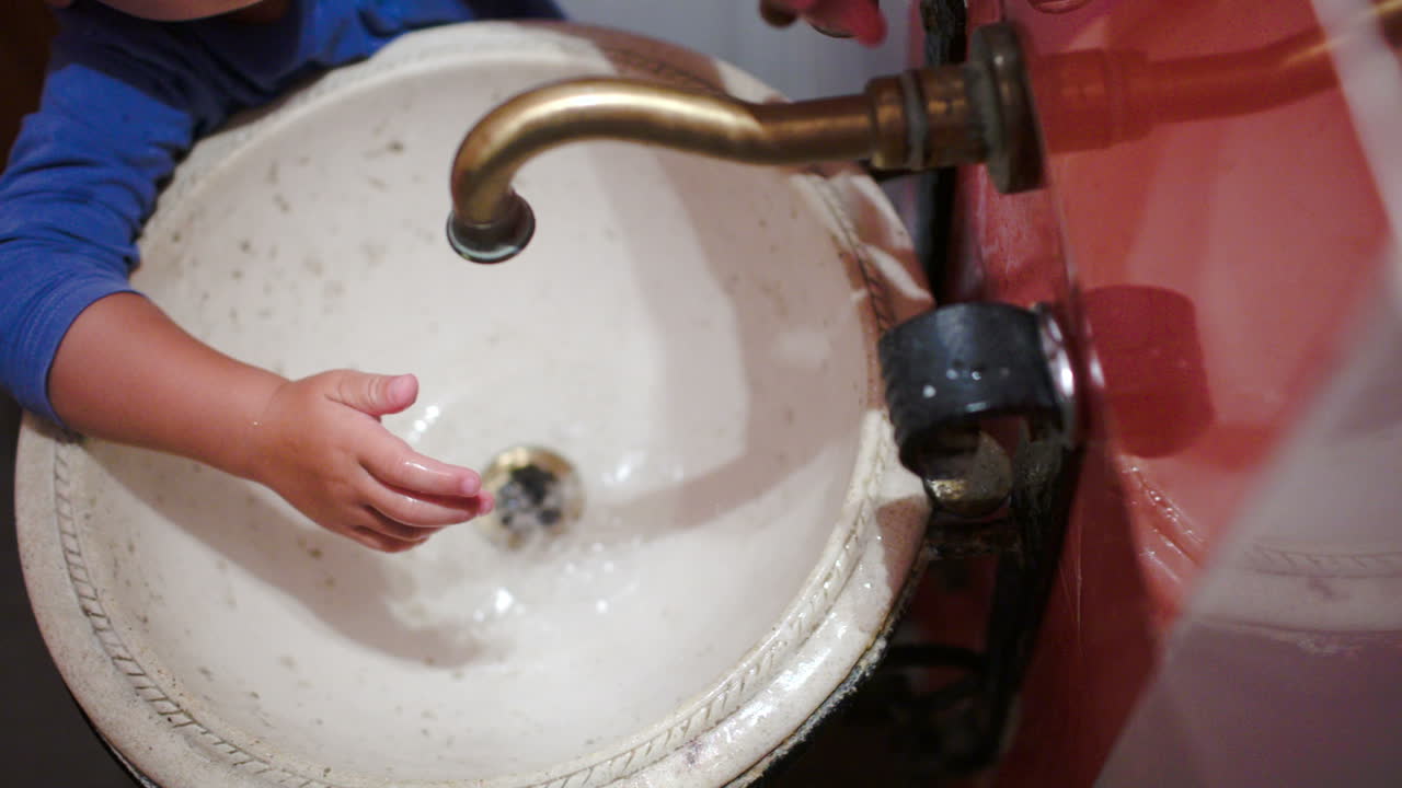 Bambino che si lava le mani in un lavandino vintage