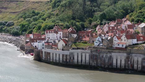 drone bird's eye view of robin hood's bay in north yorkshire, over village and houses showing ocean and charming pretty coastal village