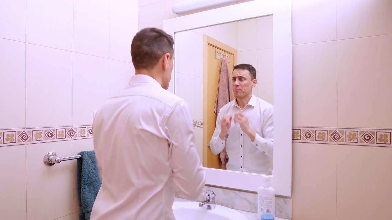 Man flossing teeth in front of bathroom mirror