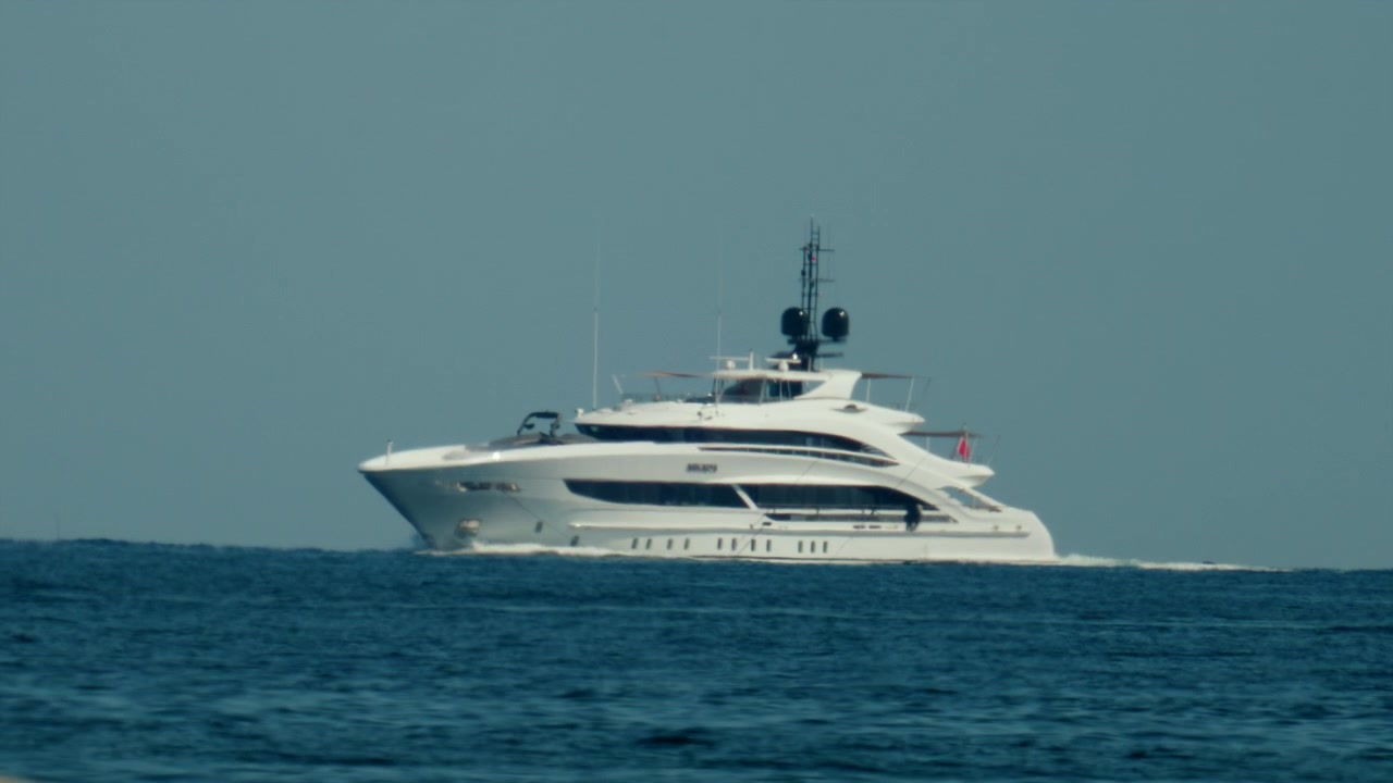 Yacht di lusso bianco che si muove sull'acqua blu dell'oceano sotto un cielo sereno, rappresentando libertà, ricchezza e fuga.
