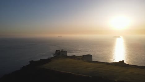 sun reflecting over sea surface at sunset and ship in background, old harry rocks cliffs