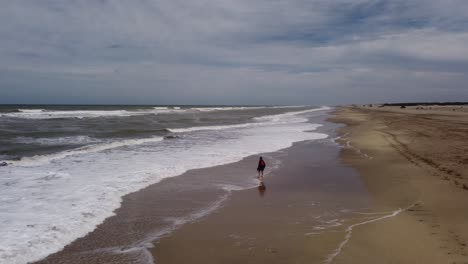 Isolated-man-walking-on-beach-seashore-on-cloudy-day