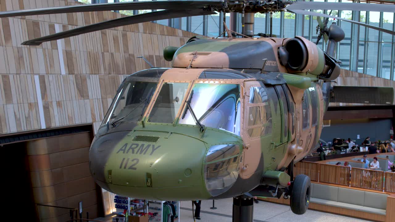 Inquadratura statica di un elicottero militare mimetizzato sospeso all'interno di uno spazio interno di un museo moderno