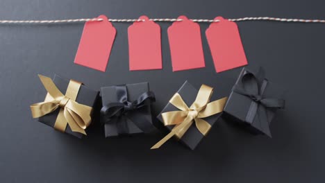 video of gift tags on string, gift boxes with ribbons and copy space on black background