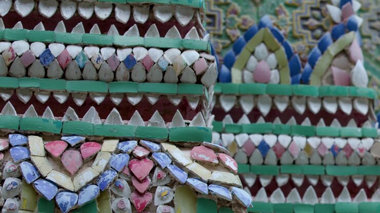 Panoramica ravvicinata sugli intricati motivi a mosaico in porcellana che adornano l'architettura della pagoda al Grand Palace di Bangkok