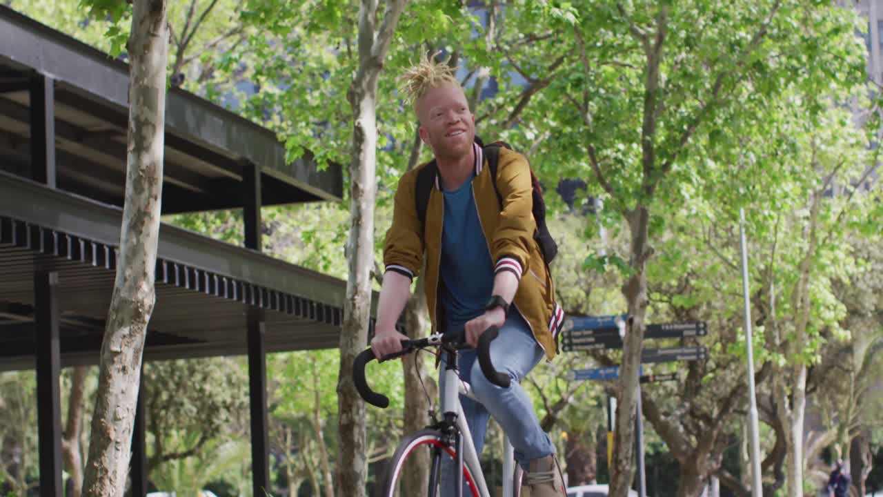 Happy albino african american man with dreadlocks riding bike