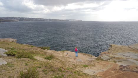 man fishing from the cliff at the pacific ocean