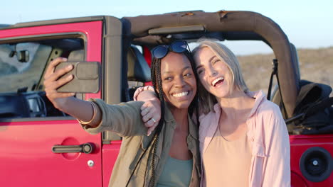 una joven afroamericana y una joven caucásica se toman una selfie al aire libre en un viaje por carretera.