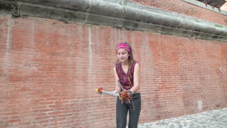 slowmotion pan of girl with dreadlocks spinning sticks as part of circus skills