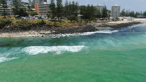 flying in fast and low, waves crashing on rocky beach waiting surfers , bright sunny day