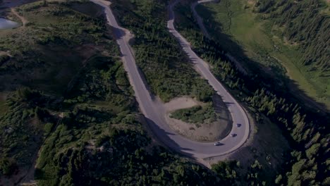 Cars-driving-around-high-elevation-winding-hairpin-turn-rocky-mountain-pass-drone-4k