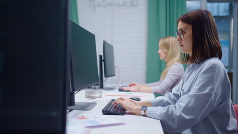two women working at a computer desk in an office