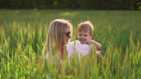 happy family having fun. baby boy with brown curly hair and his mother with ginger hair showing thumb up each other. outdoor shot