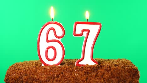 cake with the number 67 lighted candle. chroma key. green screen. isolated